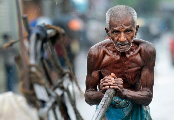 斯里兰卡首都科伦坡,一名年迈老人在雨中推着一辆手推车艰难前行
